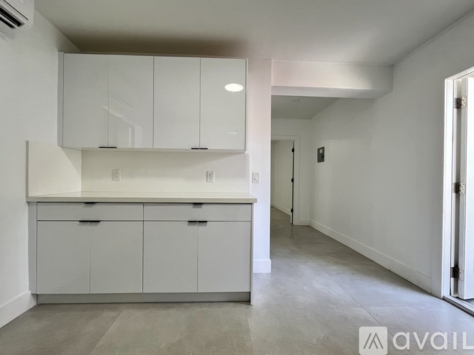A spacious room with white cabinets and a carpeted floor.