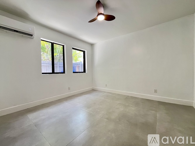 A room with a ceiling fan and two windows.