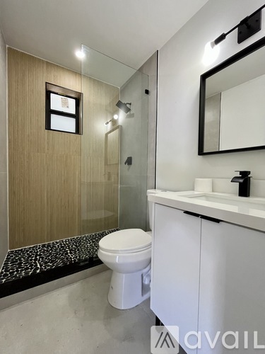 A bathroom with a toilet, sink, mirror, and a wooden wall.