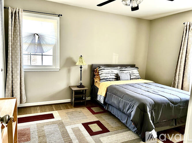 A bedroom with a bed, nightstand, and window.