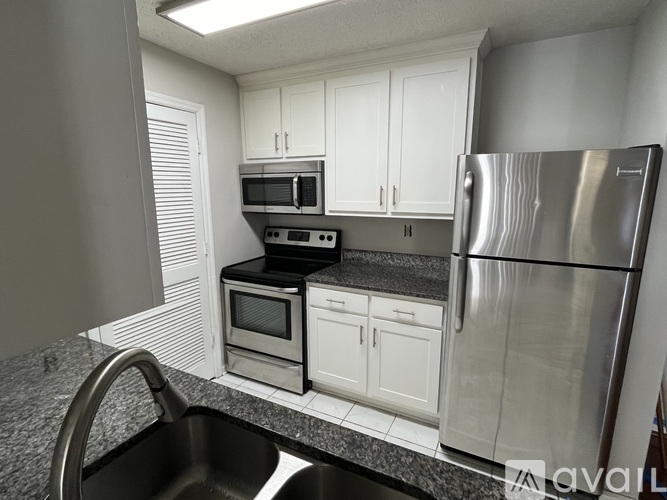 A kitchen with a stainless steel refrigerator, microwave, oven, and cabinets.