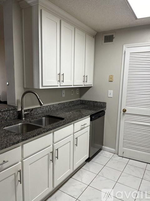 A kitchen with white cabinets and a black countertop.