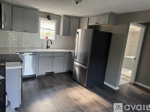 A kitchen with a stainless steel refrigerator and wooden floors.
