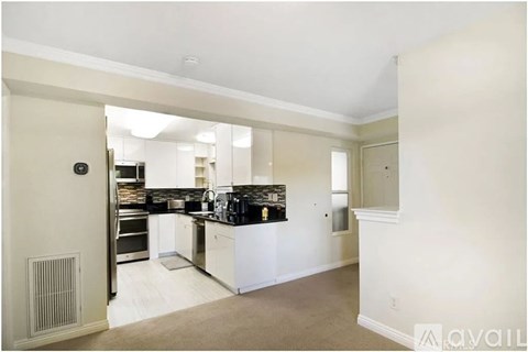 A kitchen with white cabinets and a black countertop.