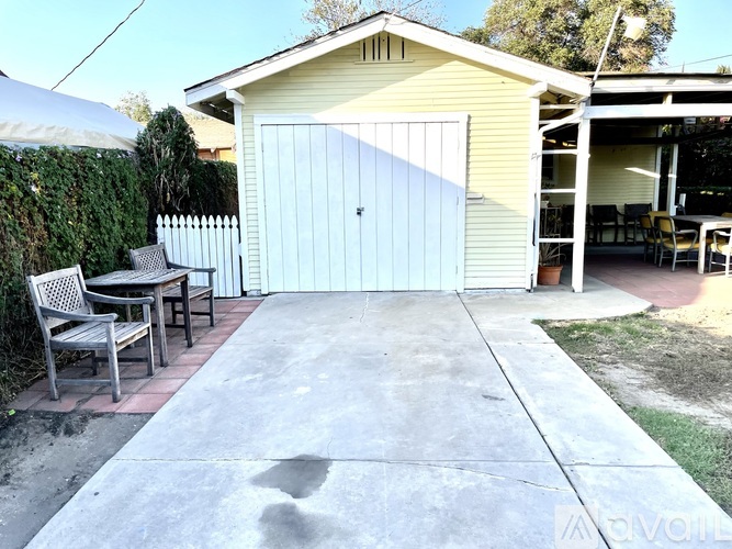A yellow house with a white garage door and a patio with a table and chairs.