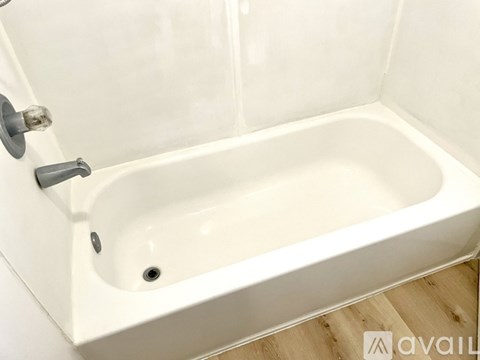 A white bathtub with a black handle is installed in a bathroom.