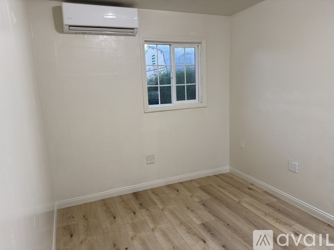 A room with a window and wooden flooring.