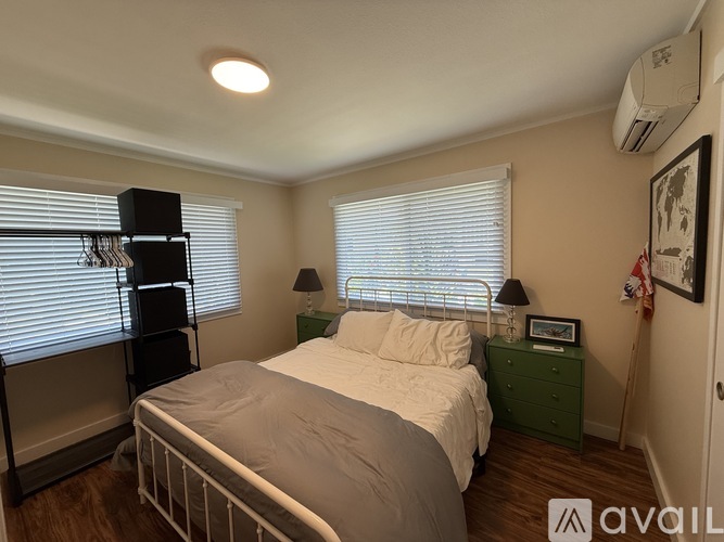 A bedroom with a bed, nightstand, and window with blinds.