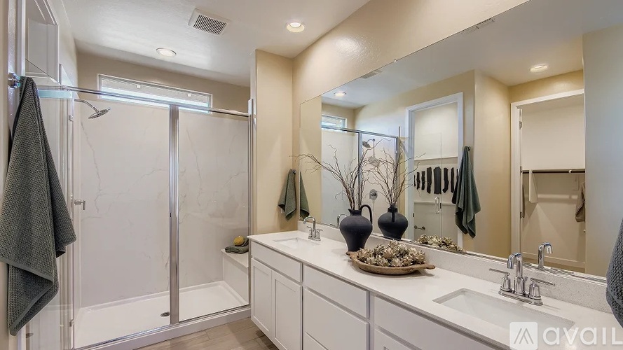 A bathroom with a white sink, mirror, and a glass shower door.