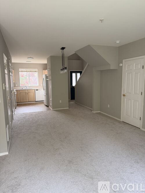 A spacious room with a carpeted floor and a staircase leading to another level.