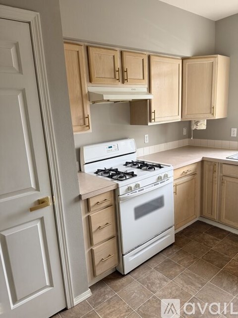 A kitchen with a white stove and wooden cabinets.