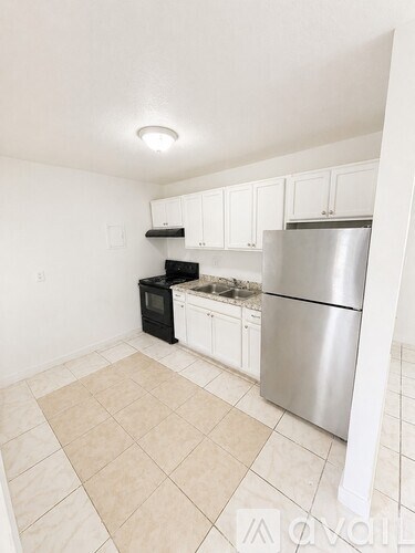 A kitchen with white cabinets and a stainless steel refrigerator.