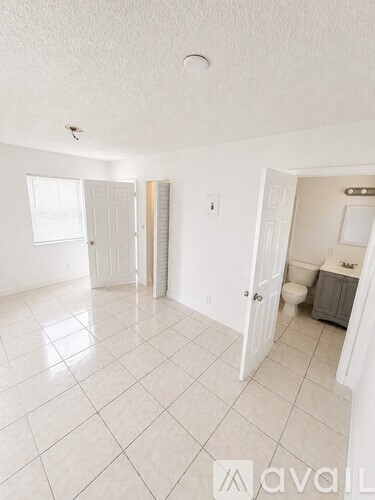 A white tiled bathroom with a toilet and sink.