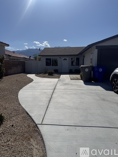 A sunny day in a residential area with a house and a car parked in the driveway.