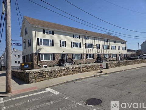 A street view of a building with a stone wall and a fire hydrant in front.