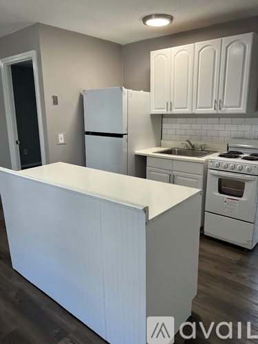 A kitchen with a white island and white appliances.