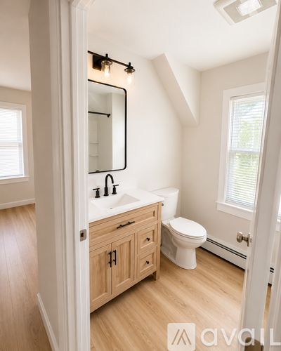 A bathroom with a toilet, sink, and mirror.