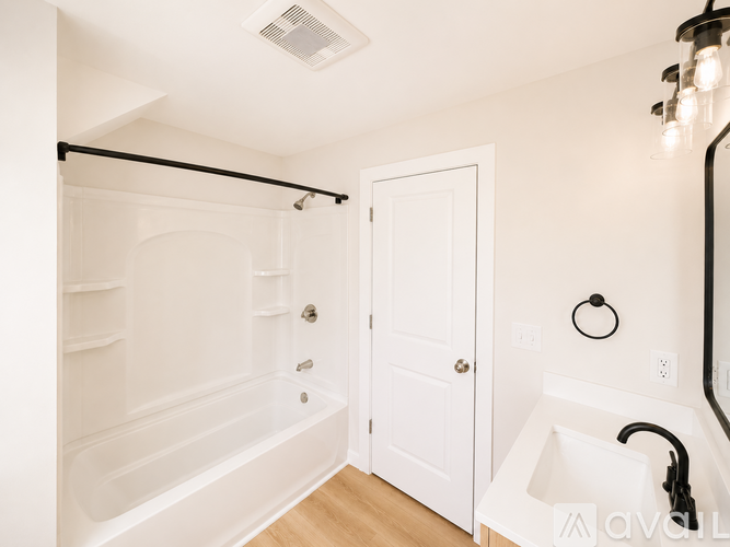 A white bathroom with a tub, sink, and mirror.