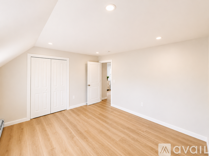 A spacious room with wooden flooring and white walls.