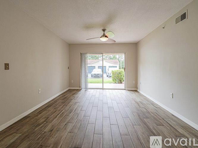 A spacious room with wooden flooring and a ceiling fan.