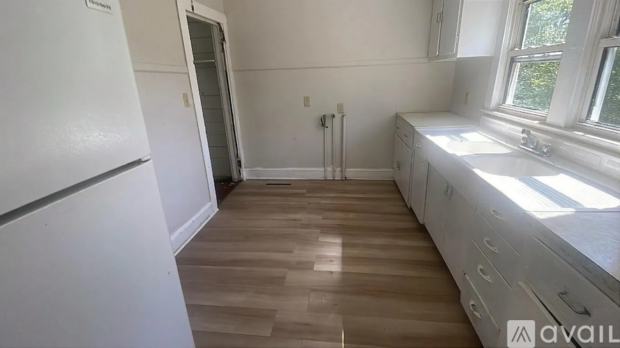 A kitchen with white appliances and wooden floors.