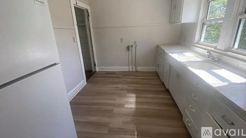 A kitchen with white appliances and wooden floors.