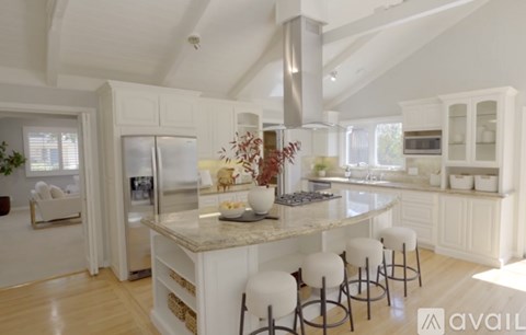 A kitchen with a marble island and white stools.