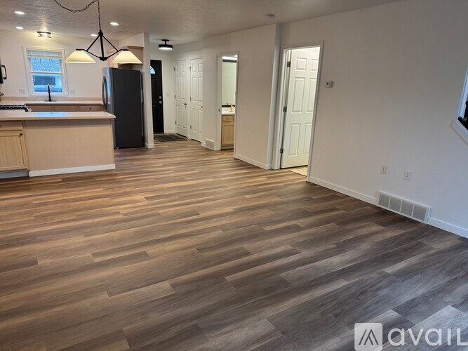 A spacious room with wooden flooring and white walls.