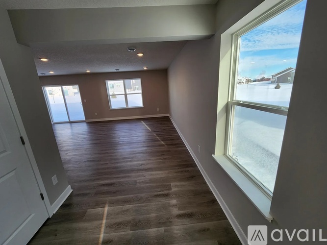 A room with wooden flooring and a large window overlooking a snowy landscape.
