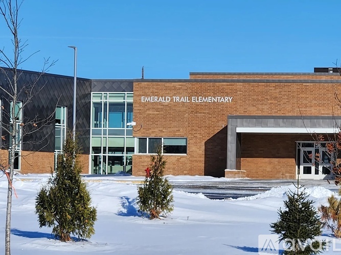 The front of the Emerald Trail Elementary school building is shown with snow on the ground and evergreens in front.