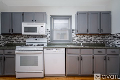 A kitchen with a white stove and dishwasher, a microwave above the stove, and grey cabinets.