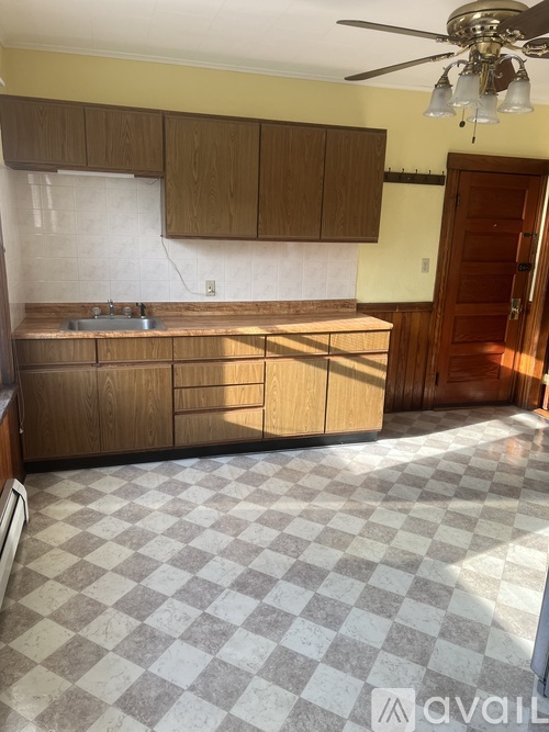 A kitchen with wooden cabinets and a checkered floor.
