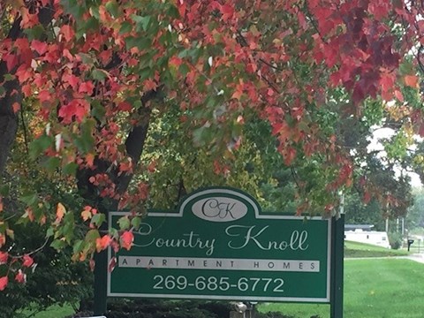 A sign for Country Knoll Apartment Homes is shown with a phone number.