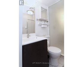 A white bathroom with a toilet, sink and mirror.