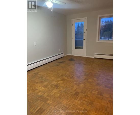 A room with wooden flooring and a door leading outside.