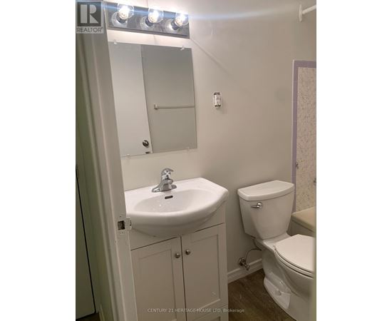 A bathroom with a sink, toilet and mirror.