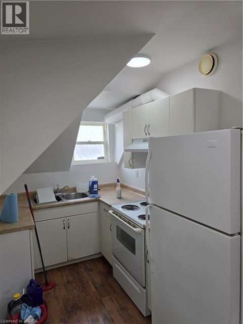 A kitchen with white appliances and wooden floors.