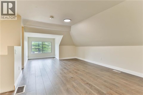 A spacious room with wooden flooring and a sliding glass door leading to a garden.