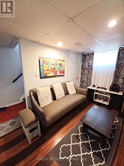 A living room with a couch, a chair, and a painting on the wall.