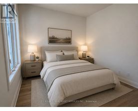 A bedroom with a large bed, two lamps, and a painting on the wall.