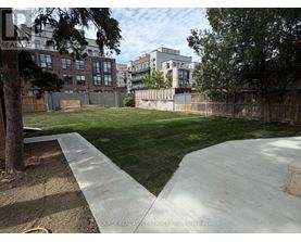 A backyard with a concrete walkway and a grassy area.