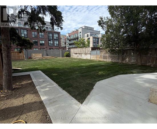 A backyard with a concrete walkway and a grassy area.