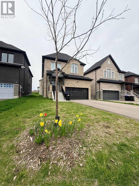 A realtor photo of a house with a tree and flowers in the front yard.