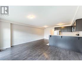 A spacious room with wooden flooring and a bar area.
