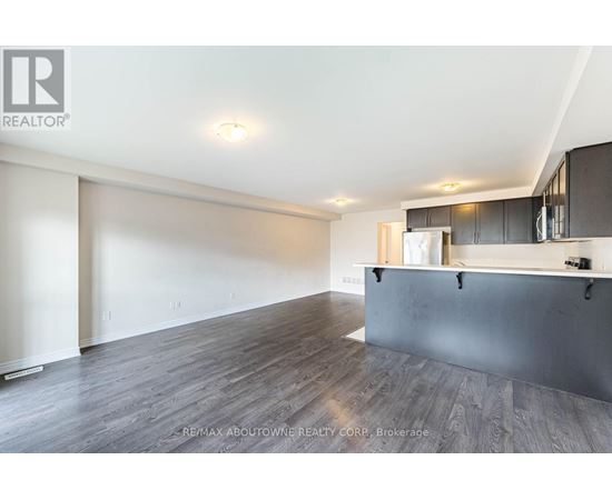 A spacious room with wooden flooring and a bar area.