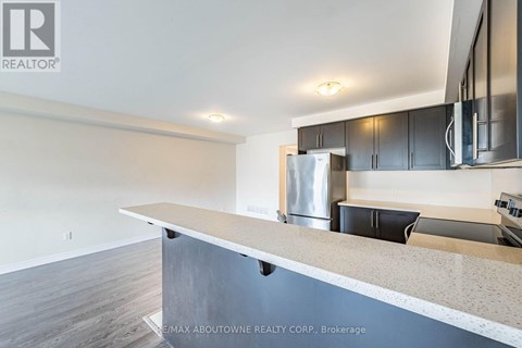 A modern kitchen with a stainless steel refrigerator and black cabinets.