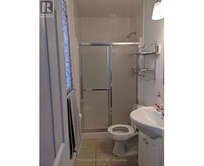 A white toilet is in a small bathroom with a glass shower door.