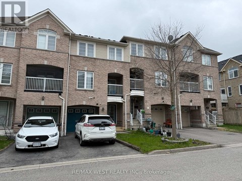 A white car is parked in front of a brick building.
