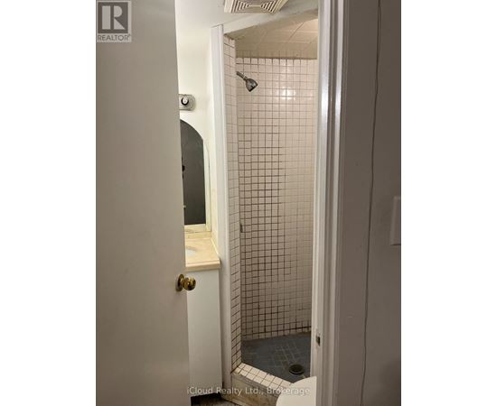 A white door with a gold handle is open to a bathroom with a tiled shower.