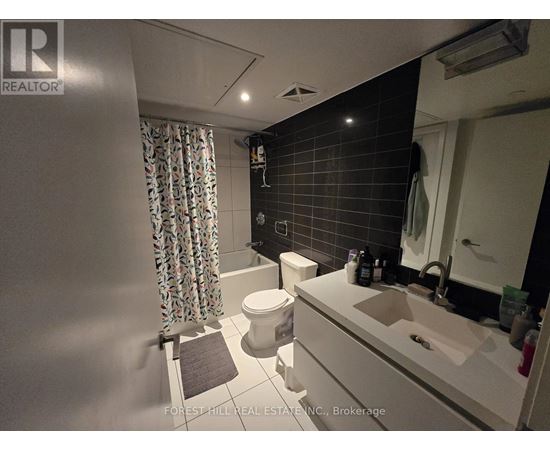 A bathroom with a toilet, sink, and shower curtain.